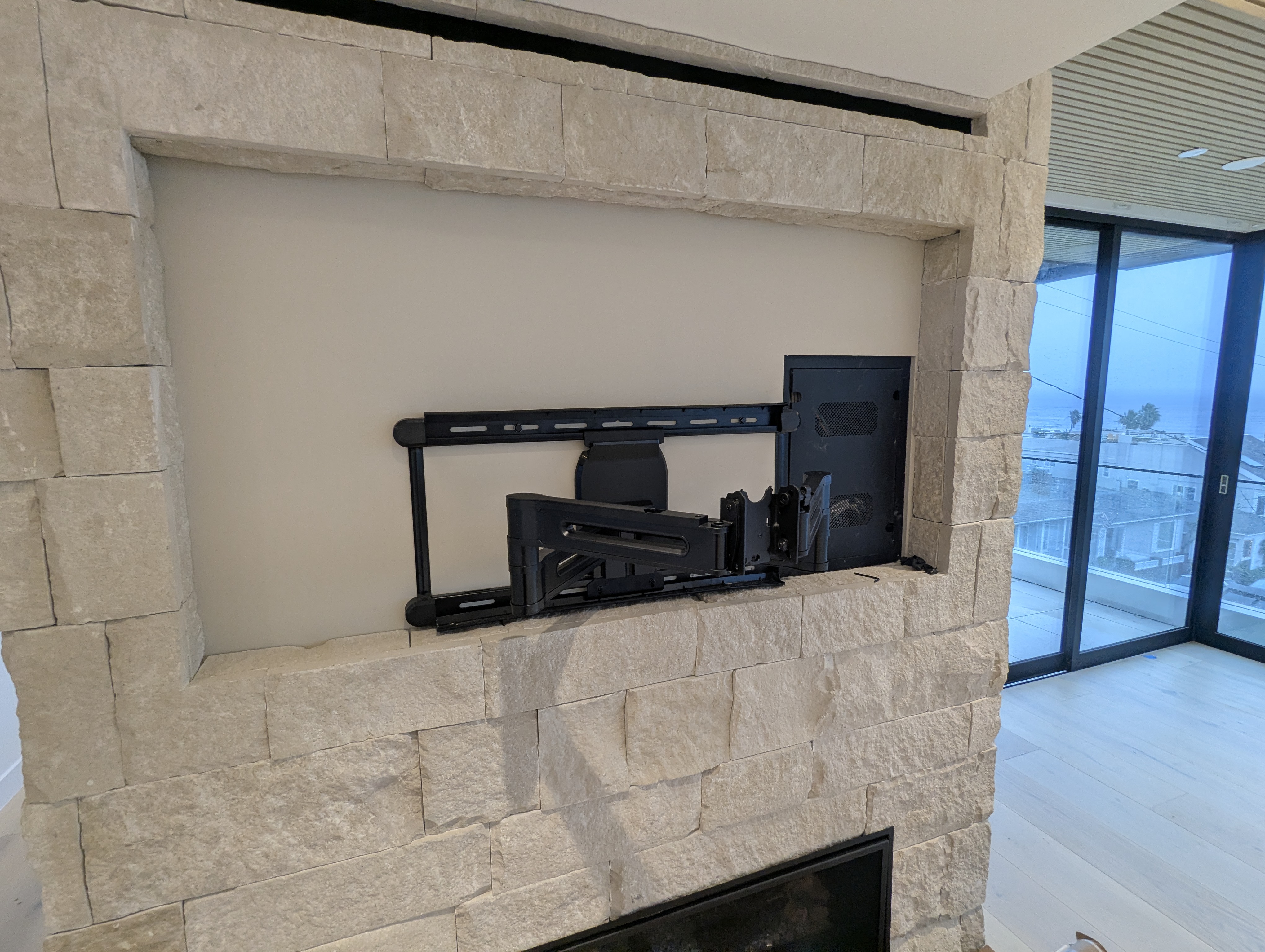 TV wall mount over stone fireplace with ocean view